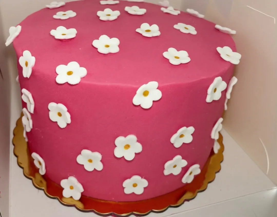Roze taart met witte bloemetjes van marsepein