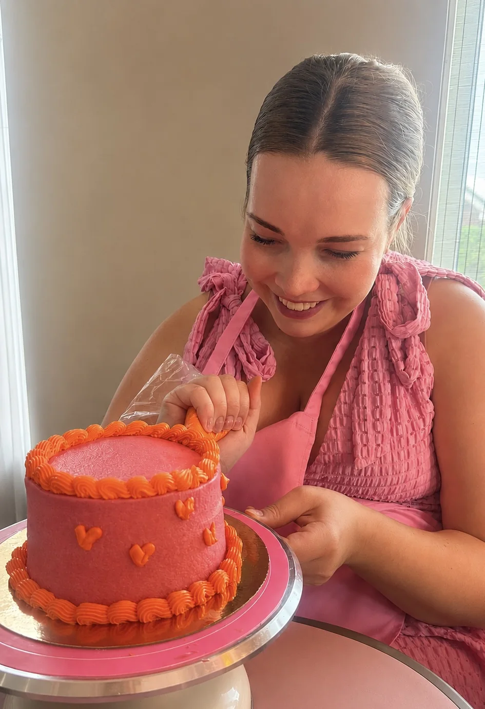 Kirsten decoreert een roze taart met oranje details