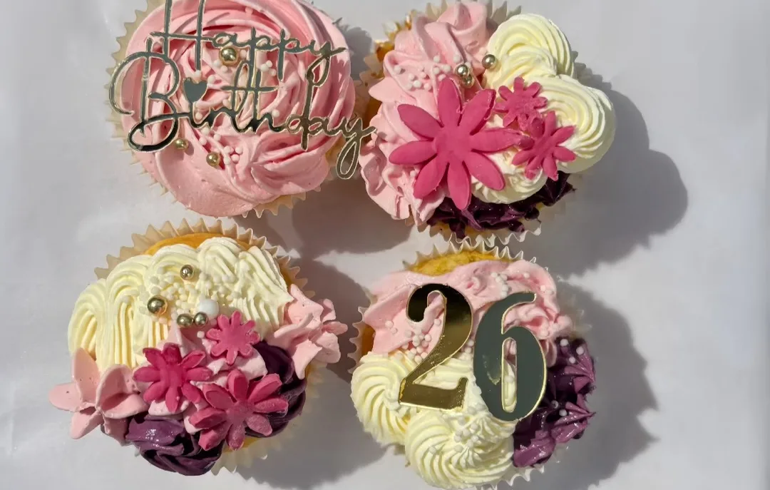Vier feestelijke cupcakes met bloemen en gouden toppers