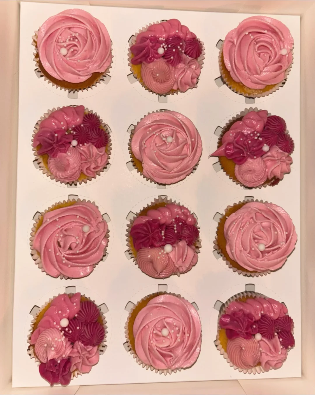 Doos met twaalf roze cupcakes in rozen-vorm